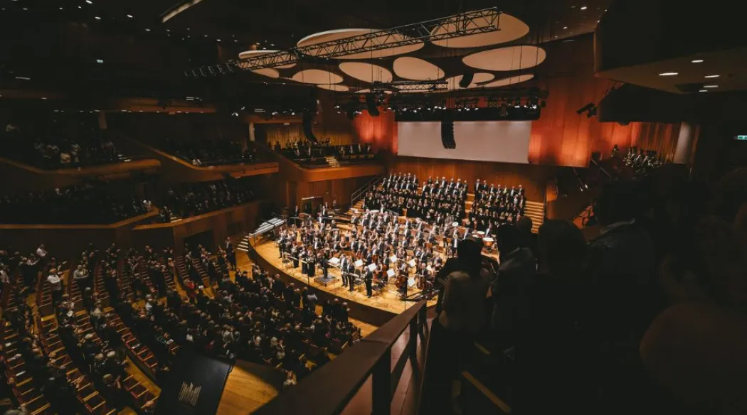 wypełniona sala koncertowa z muzykami klasycznymi na scenie