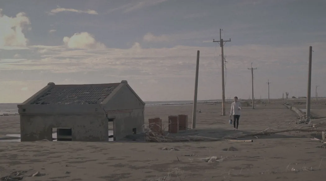 kadr z filmu pokazujący dom na plaży zasypany przez piasek