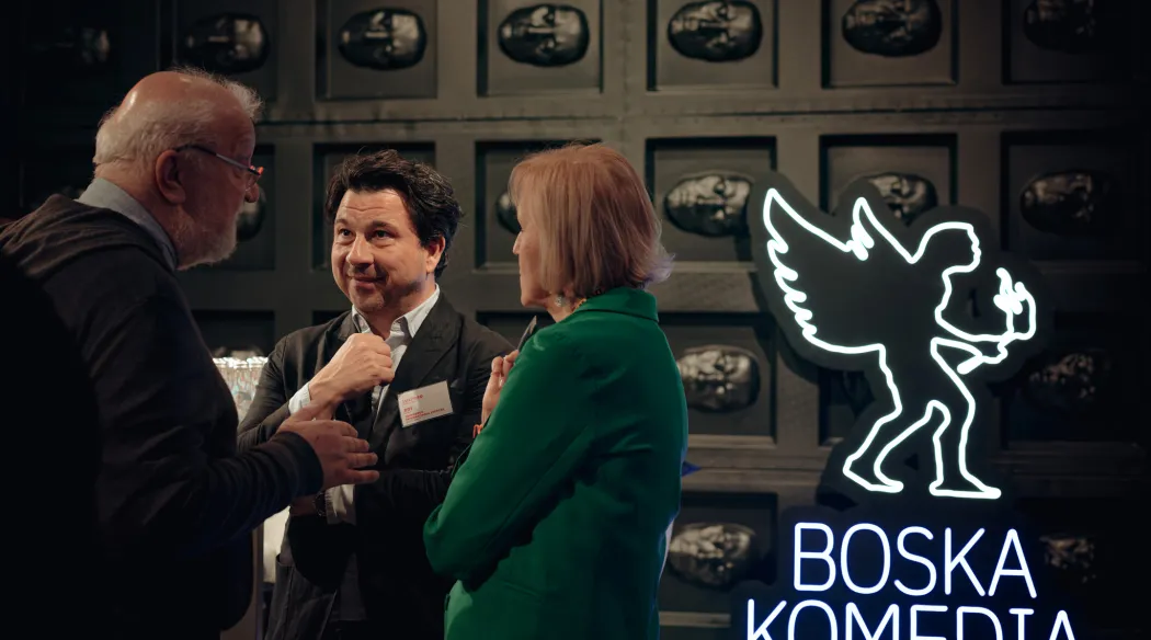 ludzie rozmawiający podczas spotkania, obok neon festiwalowy