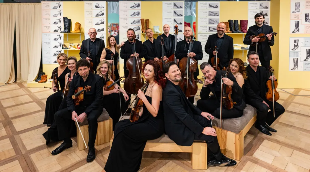 orkiestra pozuje na siedziskach, w tle dekoracja z butów