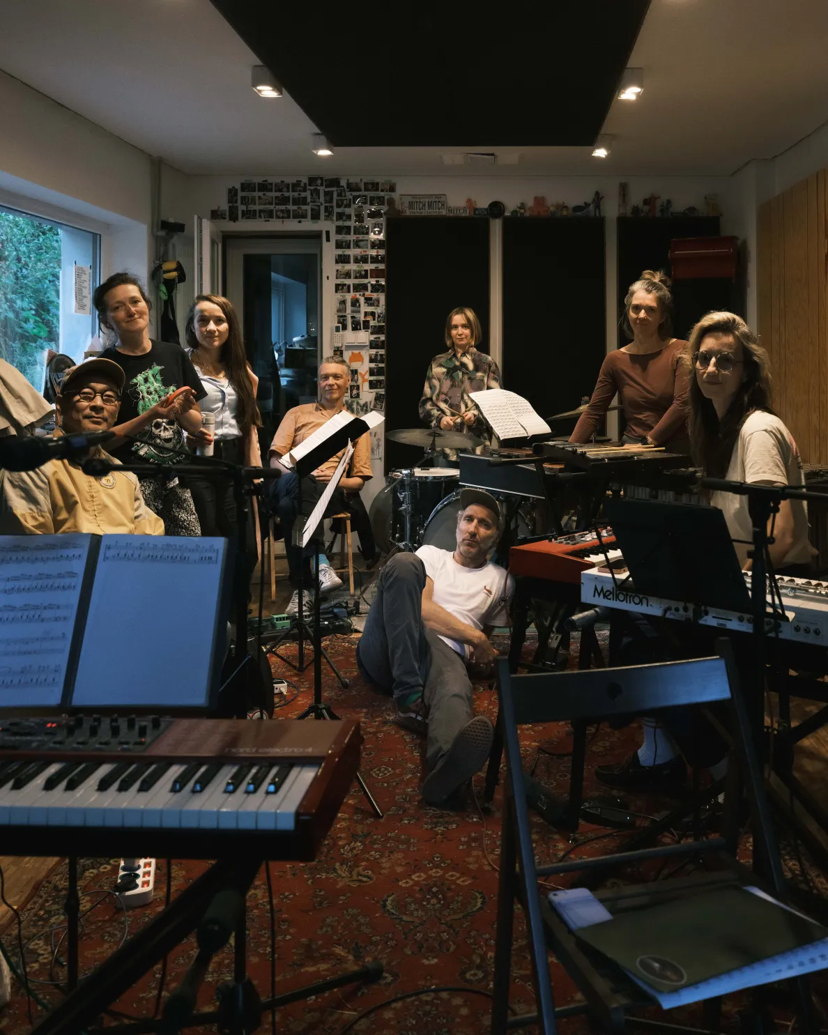 grupa muzyków w pokoju do prób pozująca do zdjęcia z instrumentami