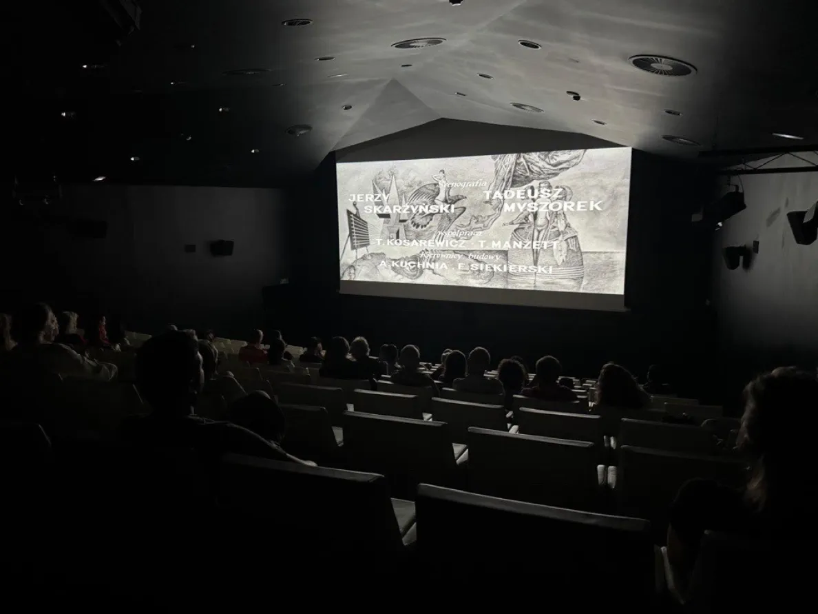 czarno-biały film wyświetlany w sali kinowej, widoczne napisy 