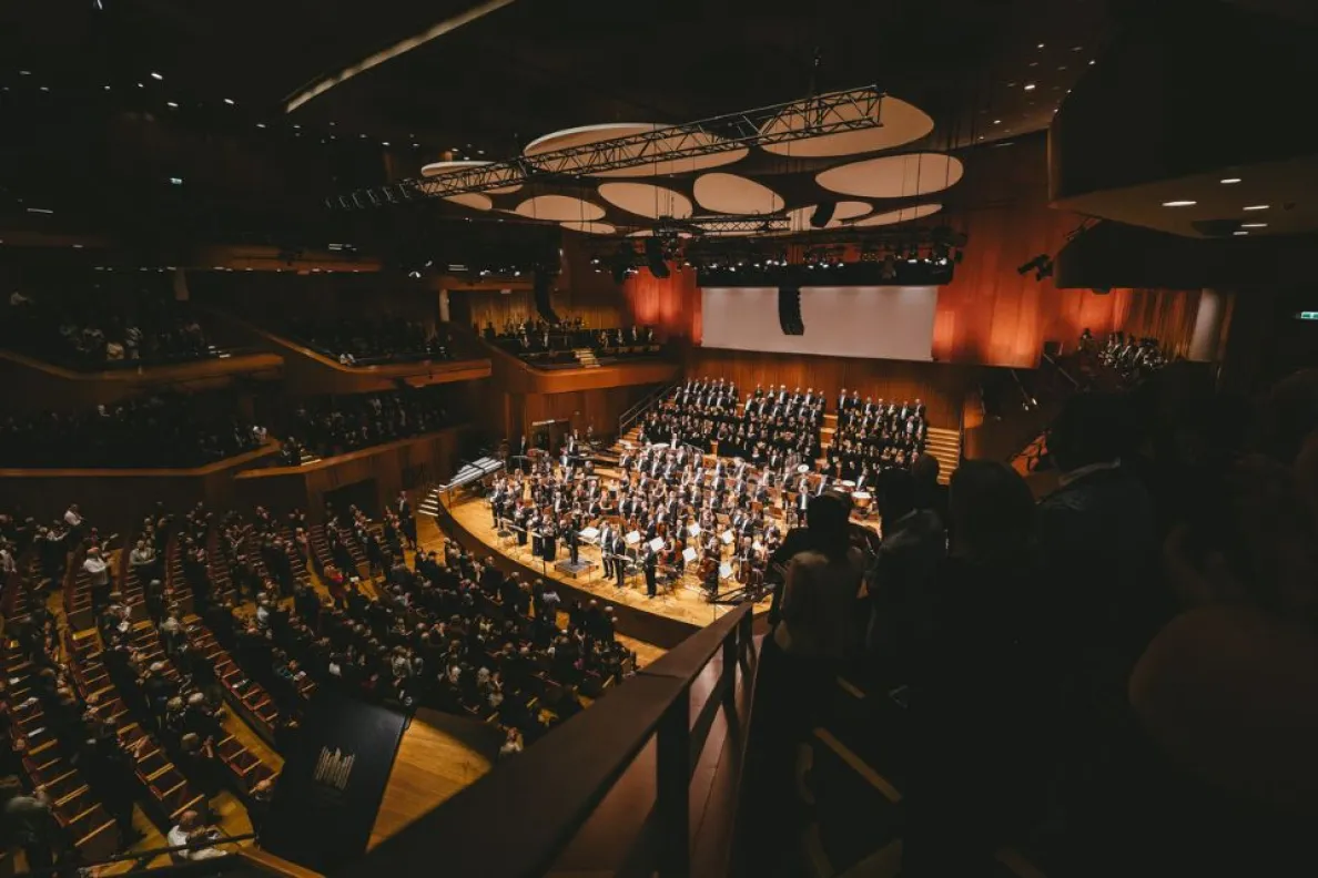 wypełniona sala koncertowa z muzykami klasycznymi na scenie