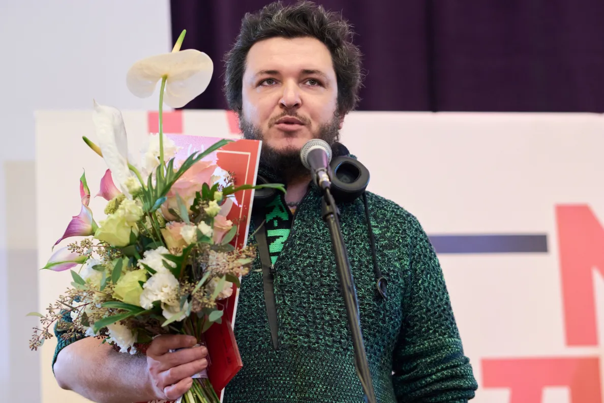 mężczyzna z kwiatami przemawia na scenie po otrzymaniu nagrody