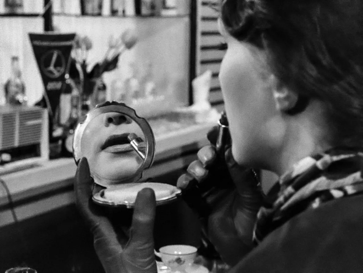 kobieta malująca usta, których odbicie widać w lusterku