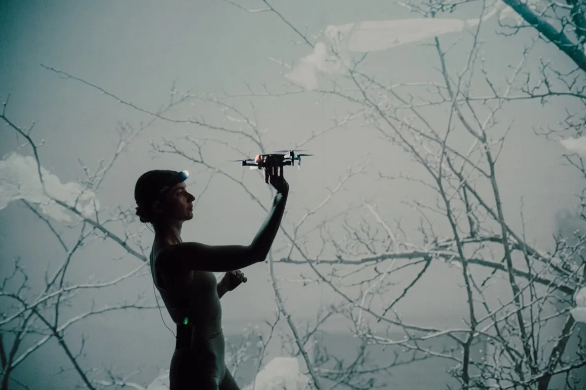 kobieta trzymająca drona na tle dramatycznej scenografii
