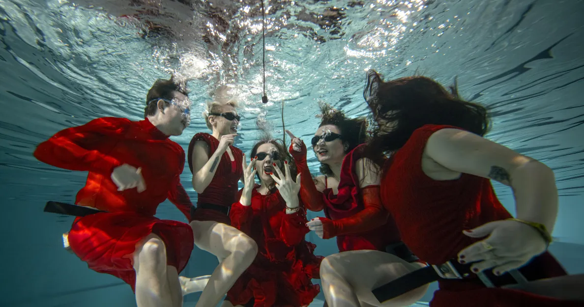 Osoby w czerwonych kostiumach pod wodą