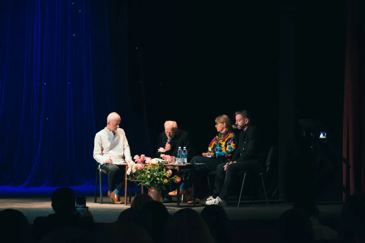 Osoby siedzące na scenie przy stole