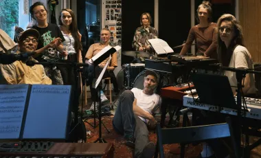 grupa muzyków w pokoju do prób pozująca do zdjęcia z instrumentami