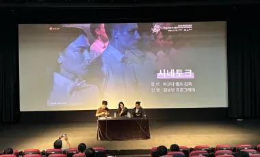 pokaz filmowy w kinie, widoczne podium z prelegentami z a którymi jest ekran z koreańskimi napisami
