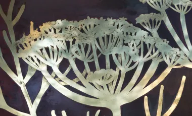 widoczny kwiat z polerowanego mosiądzu na tle oksydowanej blachy