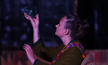 aktorka podczas występu, trzyma w ręku skałę na której skupa wzrok