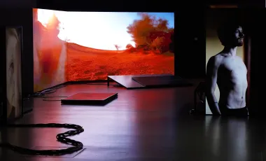 mężczyzna stoi na tle zakrzywionego ekranu pokazującego fantastyczny krajobraz