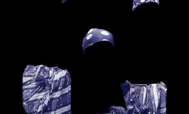 trzy kobiety ubrane w biało-niebiekie stroje, których sylwetko zostały przyciemnnione tak, że stapaiją się z tłem i widać tylko materiały