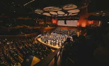 wypełniona sala koncertowa z muzykami klasycznymi na scenie