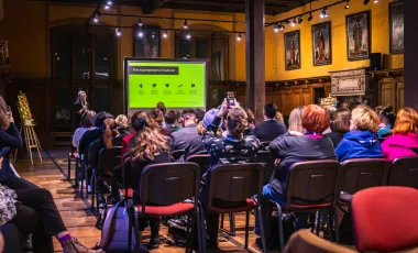 ludzie siedzący w sali słuchają wykładu 