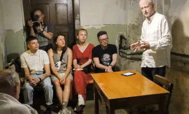 mężczyzna przemawia w schronie do zgromadzonej publiczności