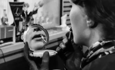 kobieta malująca usta, których odbicie widać w lusterku