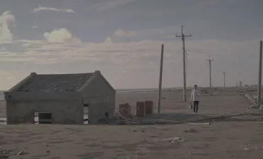 kadr z filmu pokazujący dom na plaży zasypany przez piasek