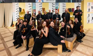 orkiestra pozuje na siedziskach, w tle dekoracja z butów