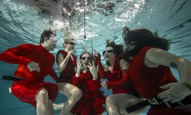 Osoby w czerwonych kostiumach pod wodą
