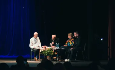 Osoby siedzące na scenie przy stole