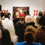 tłum gości zgromadzonych na wernisażu ogląda prace i słucha przemówienia kuratorów