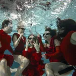 Osoby w czerwonych kostiumach pod wodą