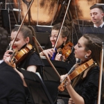 koncert na scenie trzy skrzypaczki z instrumentami  