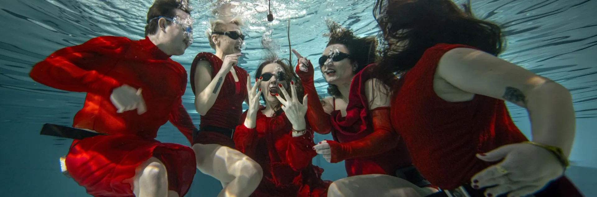 Osoby w czerwonych kostiumach pod wodą