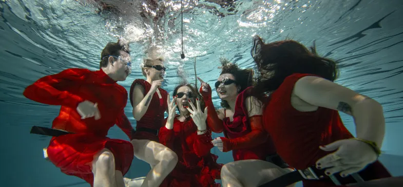 Osoby w czerwonych kostiumach pod wodą